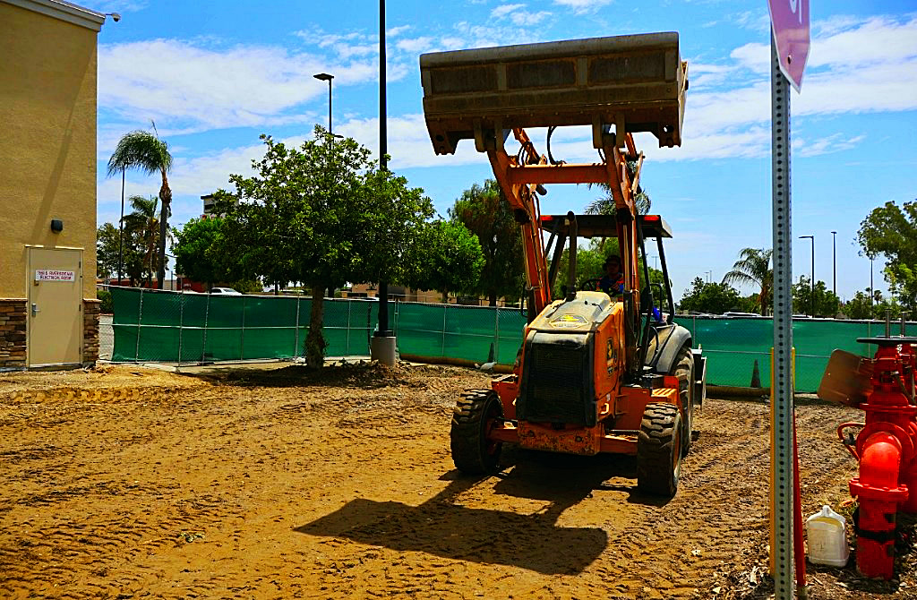 Skip loader moving material across the graded pad